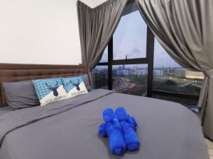 新山Mid Valley Southkey Mosaic Cozy Suite at Johor Bahru的一张靠窗的床上一双蓝色手套