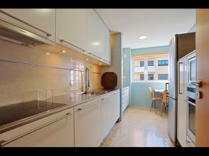 里斯本世博会舒适当代旅馆的厨房配有白色橱柜、水槽和桌子