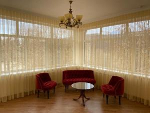 纳尔奇克科罗纳酒店的一间设有红色椅子和一张桌子及窗户的房间