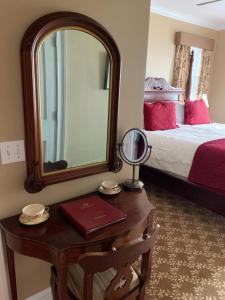 纽波特Almondy Inn Bed & Breakfast的卧室配有镜子和一张桌子及一张床