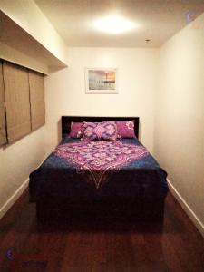 马尼拉BGC Fort Victoria的一间卧室配有一张床铺,床上铺有紫色毯子
