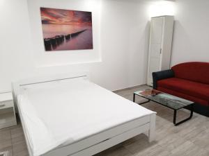 贝尔格莱德Airport view Apartment的卧室配有白色的床和红色沙发