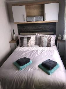 沃切特3 bed presitage caravan Doniford Bay的一张白色的床,上面有两个枕头