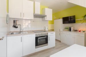 博希尼Apartments Green Paradise的白色的厨房配有白色橱柜和水槽