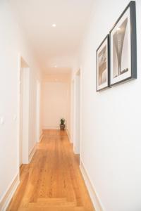 里斯本里斯本欣悦公寓的走廊设有白色墙壁和硬木地板