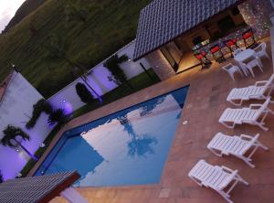 里约达斯弗洛雷斯Kings International Hotel的享有带白色桌椅的游泳池的顶部景致