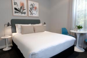 悉尼The Alison Randwick的卧室配有白色的床、两张桌子和一扇窗户