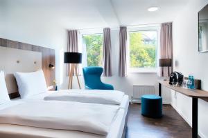 斯图加特ACHAT Hotel Stuttgart Zuffenhausen的酒店客房,设有两张床和一张蓝色椅子