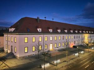新特劳布灵Apartment:house Klosterbau的一座白色的大建筑,晚上有红色屋顶