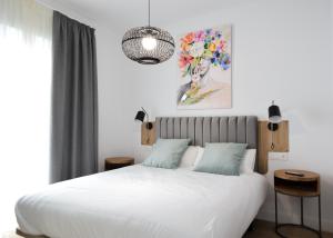 塞维利亚Calma Suites的卧室配有白色的床和墙上的绘画作品