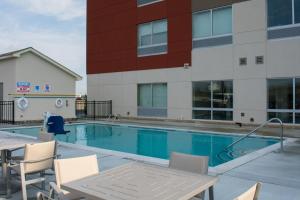 西孟菲斯Holiday Inn Express & Suites West Memphis, an IHG Hotel的一座带椅子的游泳池以及一座建筑