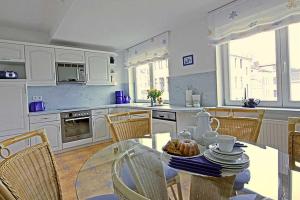 诺伊霍夫Villa Seestern _ Wohnung 10的厨房配有玻璃桌、椅子和桌子