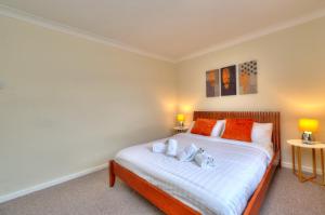斯蒂夫尼奇Hampson House Stevenage by PAY AS U STAY的一间卧室配有带橙色和白色枕头的床