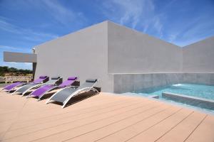巴古尔Casa Lou, architect villa with heated pool at Begur, 470m2的一组椅子坐在游泳池旁的甲板上