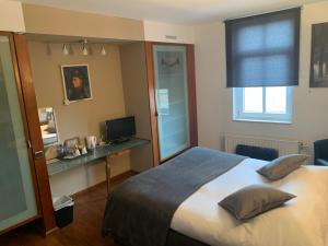 滑铁卢乐1815酒店的一间卧室配有一张床、一张书桌和一个窗户。