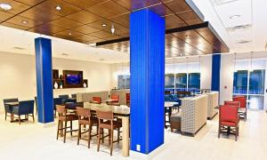 PerryvilleHoliday Inn Express & Suites - Perryville I-55, an IHG Hotel的一间设有蓝色圆柱和桌椅的餐厅
