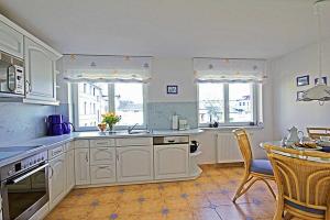 诺伊霍夫Villa Seestern _ Wohnung 10的厨房配有白色橱柜和桌椅