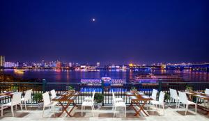 武汉武汉晴川假日酒店 的餐厅设有桌椅,俯瞰着水域