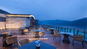 淳安Crowne Plaza Hangzhou Thousand Island Lake, an IHG Hotel的一间在甲板上配有桌椅的餐厅