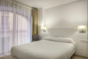 塔拉戈纳Apartaments Lauria的卧室配有白色的床和窗户。