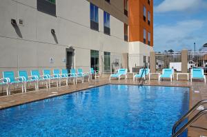 查尔斯湖Holiday Inn Express & Suites - Lake Charles South Casino Area, an IHG Hotel的一座带蓝色椅子的游泳池和一座建筑