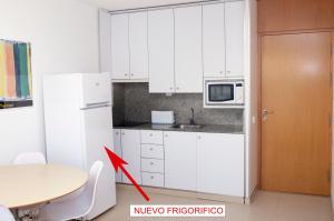 马塔拉斯卡尼亚斯Apartamento con vistas al mar primera linea playa Matalascañas的厨房配有白色橱柜、桌子和红色箭头