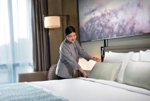 上海上海建工浦江皇冠假日酒店的站在酒店房间床边的女人