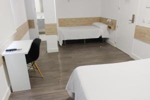 梅里达Deluxe Hostels & Suites Merida的小房间设有两张床、一张桌子和椅子