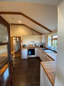 卡姆尔福德Sundance Cottage Sleeps 4 plus 2的厨房配有白色橱柜和棕色瓷砖地板。