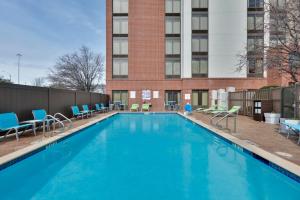 欧文Holiday Inn Express & Suites Irving Conv Ctr - Las Colinas, an IHG Hotel的一座带椅子的大型游泳池和一座建筑