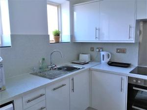 里辛Heron's View的厨房配有白色橱柜和水槽