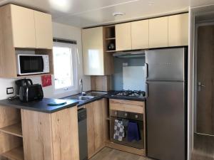 波讷地区圣朱利安Mobile Home - Les Dunes de Contis的厨房配有不锈钢冰箱和橱柜