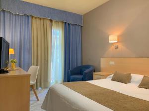 圣卡洛斯拉腊皮塔Hotel Restaurant Llansola的酒店客房设有一张床、一张书桌和一台电视机。