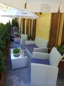 塞纳莱斯Gasthof Neuratheis的庭院配有白色藤椅和遮阳伞。