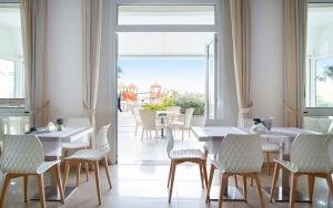 贝拉里亚-伊贾马里纳里维埃拉酒店的餐厅设有白色的桌椅和大窗户