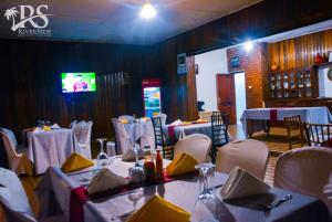 卡巴莱Riverside Resort Hotel Kabale的一间带桌子和白色椅子的用餐室以及电视