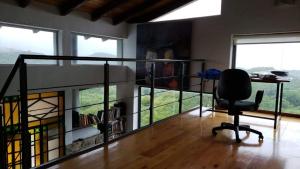 温基约Casa en las Sierras de Córdoba的一间办公室,在带窗户的房间里配有一张桌子和一把椅子