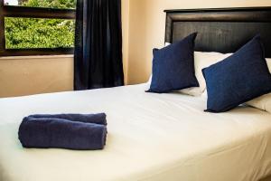 阿曼济姆托蒂Seven Seas SA的一张带蓝色枕头的白色大床和窗户