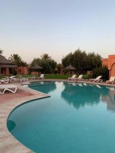马拉喀什Villa avec piscine a Marrakech的一个带椅子和遮阳伞的大型蓝色游泳池