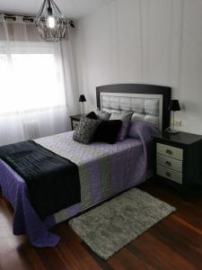 马林Casa Álvaro的一间卧室配有一张带紫色棉被的床和窗户。