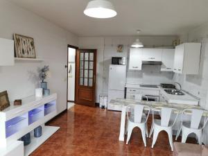 马林Casa Álvaro的厨房配有白色橱柜和桌椅