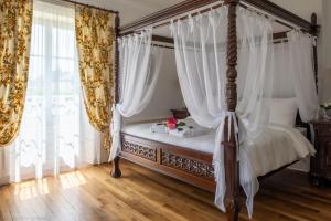 迪塞Maison d'hôtes de charme La Rose de Ducey près du Mont Saint Michel的卧室配有带白色窗帘的天蓬床
