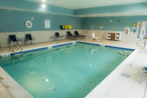 梅里尔维尔Holiday Inn Express & Suites - Merrillville, an IHG Hotel的一个带桌椅的健身房内的游泳池