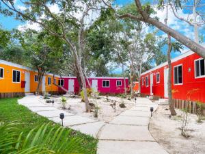 图卢姆Colorbox beds and rooms的一堆色彩缤纷的房屋,有树木和人行道