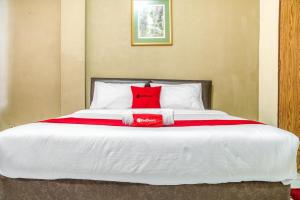 雅加达RedDoorz near Plaza Senayan的一张大床,上面有红色枕头