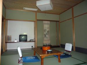 京都高尾山观光酒店的客厅配有桌子和电视