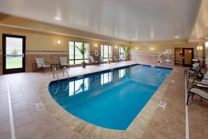 克利尔菲尔德克利尔菲尔德快捷假日酒店及套房的酒店的大型游泳池配有桌椅