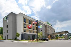 布赖恩特Holiday Inn Express and Suites Bryant - Benton Area, an IHG Hotel的加油站前有旗帜的酒店