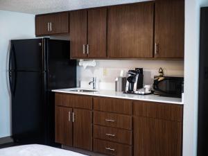 康科德Holiday Inn Express & Suites Charlotte-Concord-I-85, an IHG Hotel的厨房配有木制橱柜和黑色冰箱。