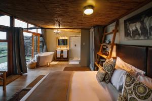 纳姆比提动物保护区Cheetah Ridge Lodge的一间卧室配有一张床,浴室设有浴缸